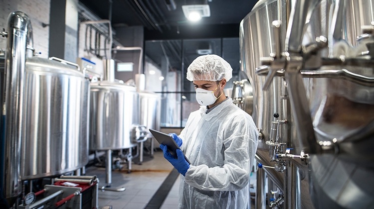 technologist-white-protective-clothes-checking-production-his-tablet