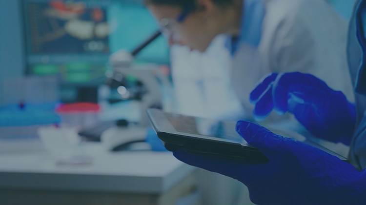 close-up-scientist-writing-tablet-while-team-biologists-doing-biological-researches-microscope-backgorund-late-night
