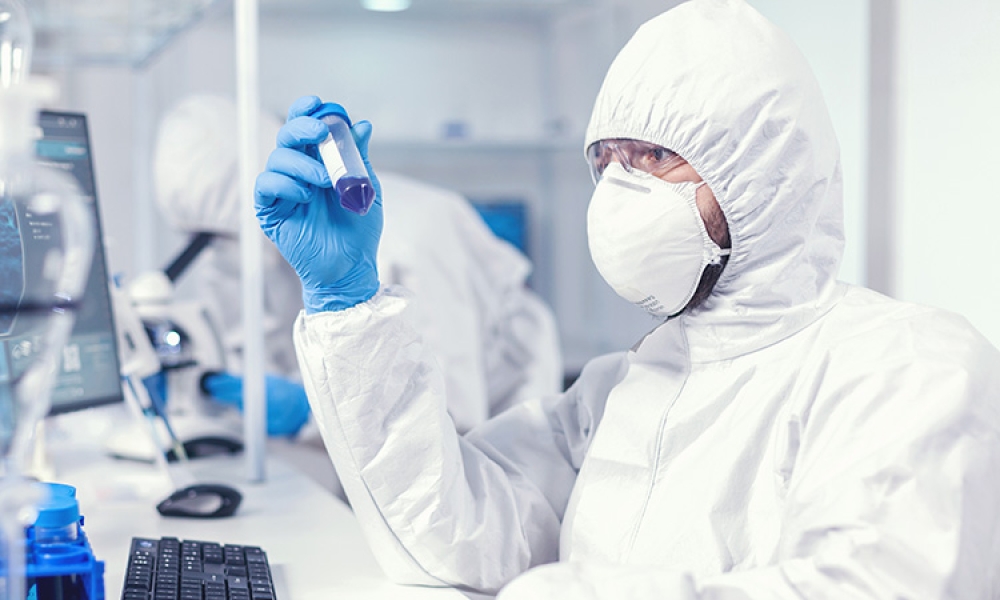 lab-technician-dressed-protective-suit-as-safety-precaution-looking-test-tube