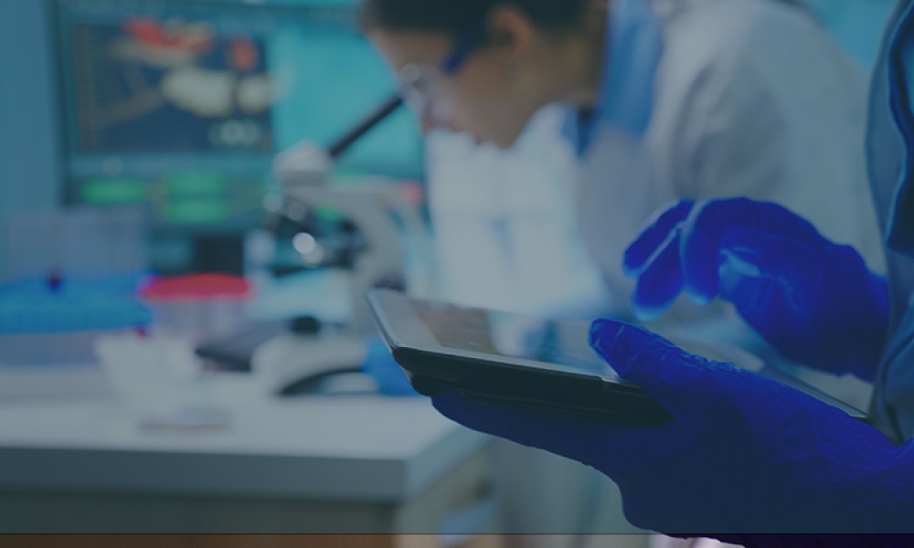 close-up-scientist-writing-tablet-while-team-biologists-doing-biological-researches-microscope-backgorund-late-night
